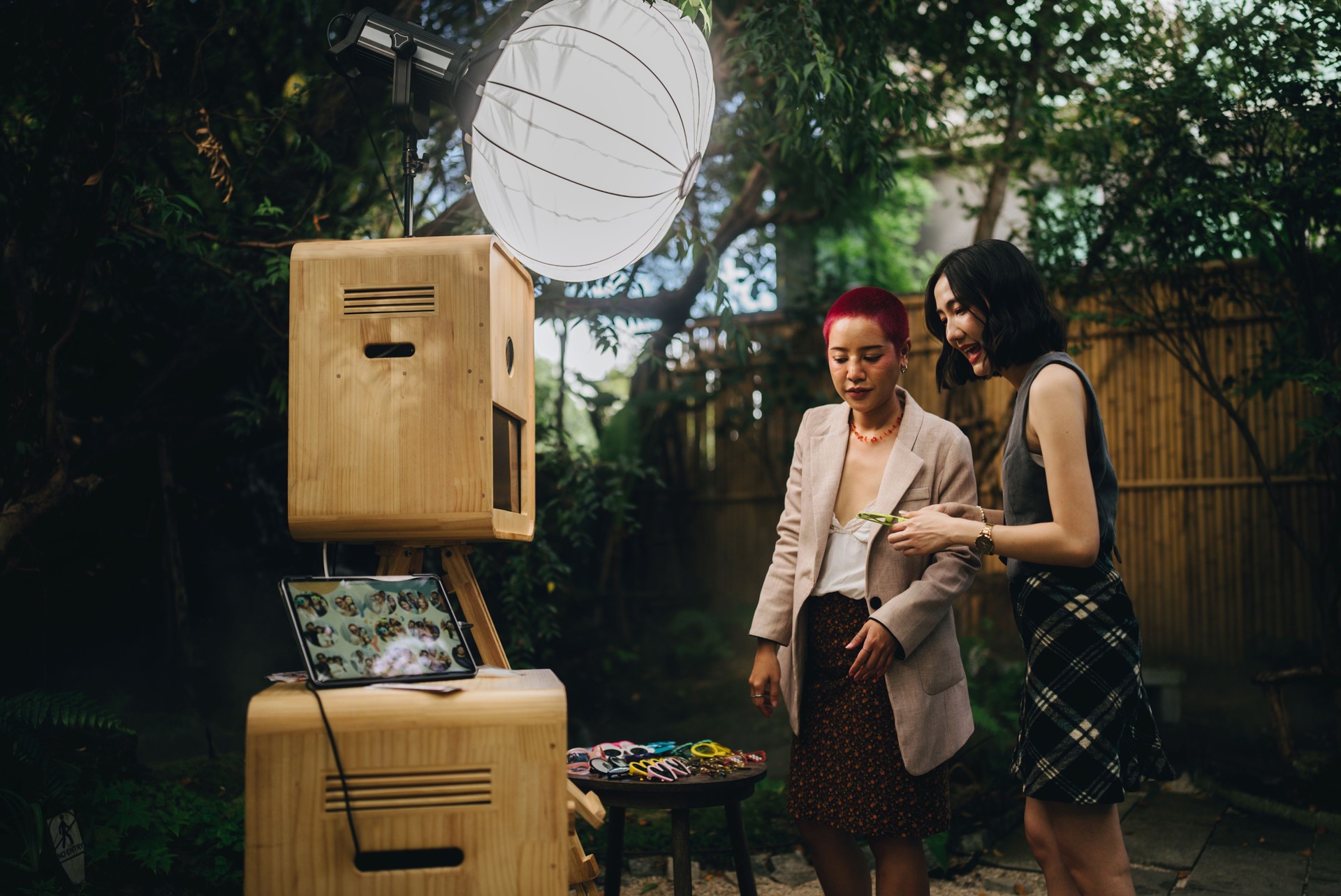Female friends having fun at a wedding in front of a photo booth Take a photo and choose to save it on a mobile phone.